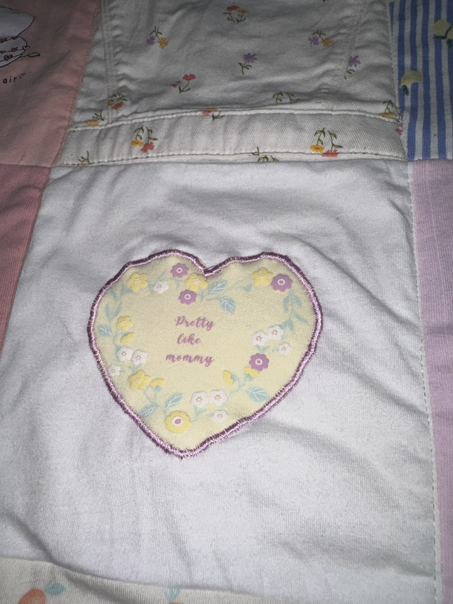 Heart-shaped detail from baby clothing preserved on a fabric square